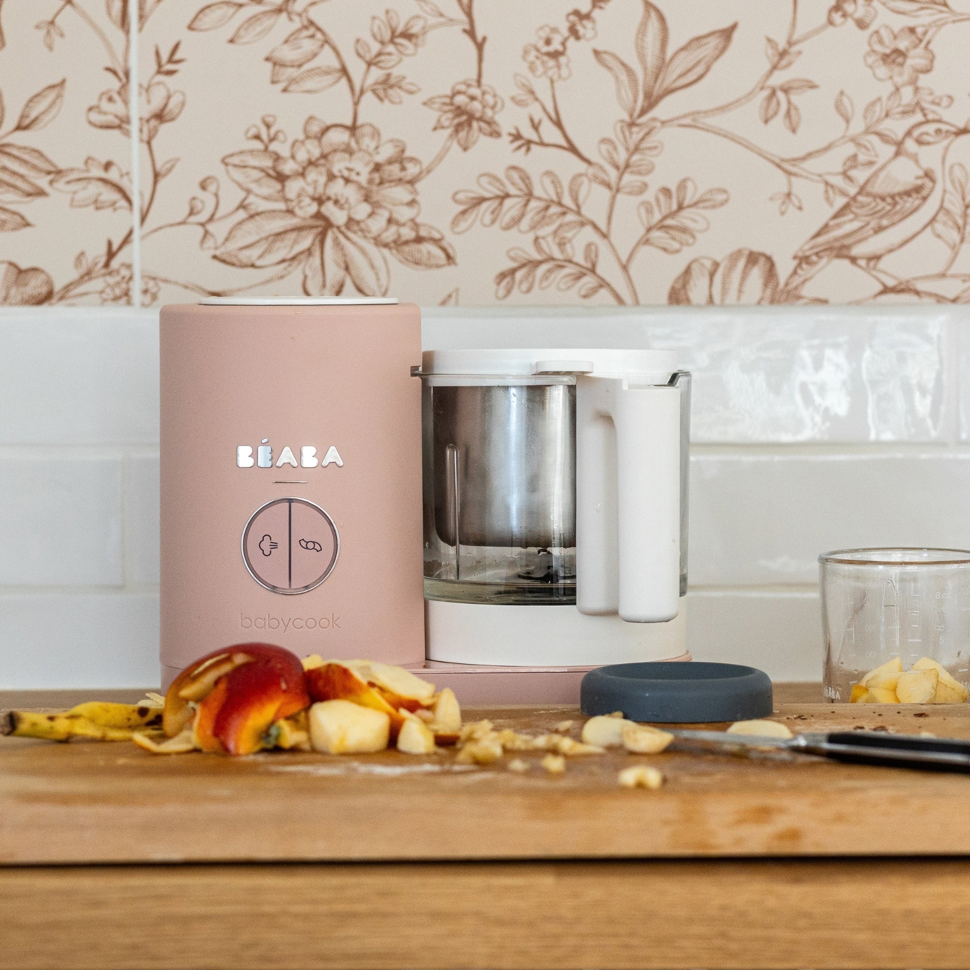 Babycook Neo Cotton Candy sitting on a wooden counter top with chopped fruit in front of it