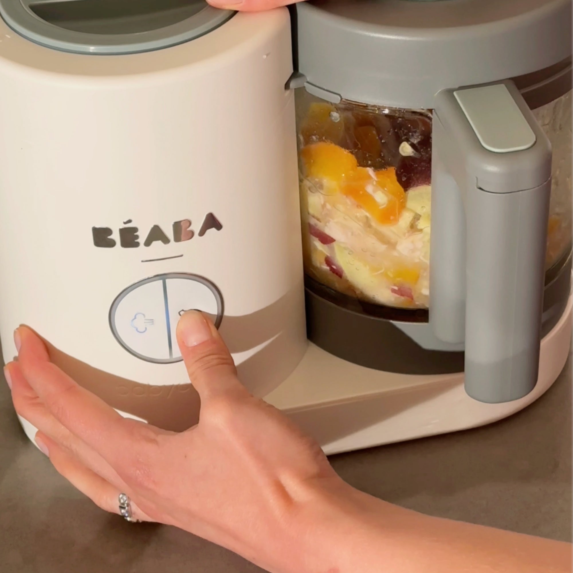 Hand pressing the blend button on Babycook bowl to make nectarine chicken puree